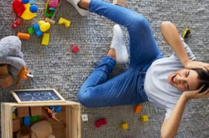 Mulher sentada no chão com expressão de exaustão por causa de burnout em donas de casa.