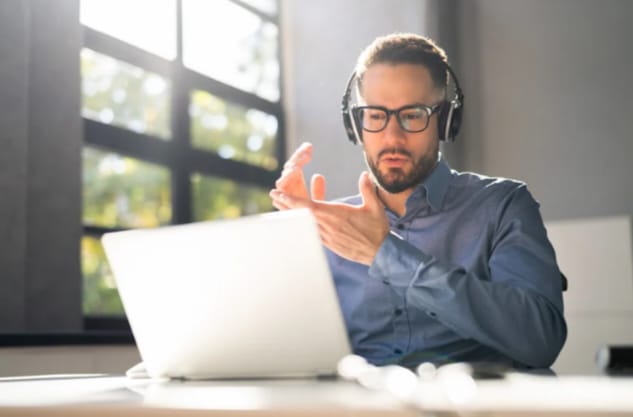 Homem em frente ao laptop em uma sessão de terapia com psicólogo online.