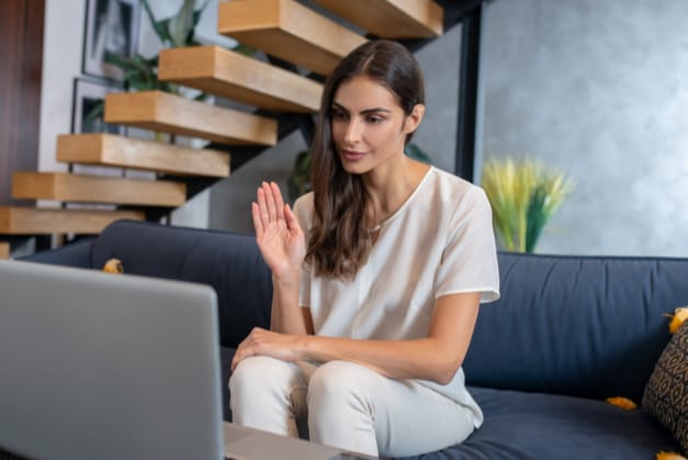 Mulher acenando em frente ao computador durante terapia online em Brasília.