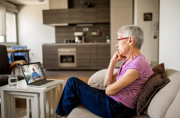 Idosa olhando para o computador em uma sessão de terapia online para brasileiros.