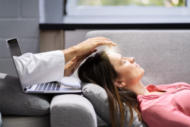 A imagem mostra uma mulher deitada em um sofá durante uma sessão com terapeuta reiki online.